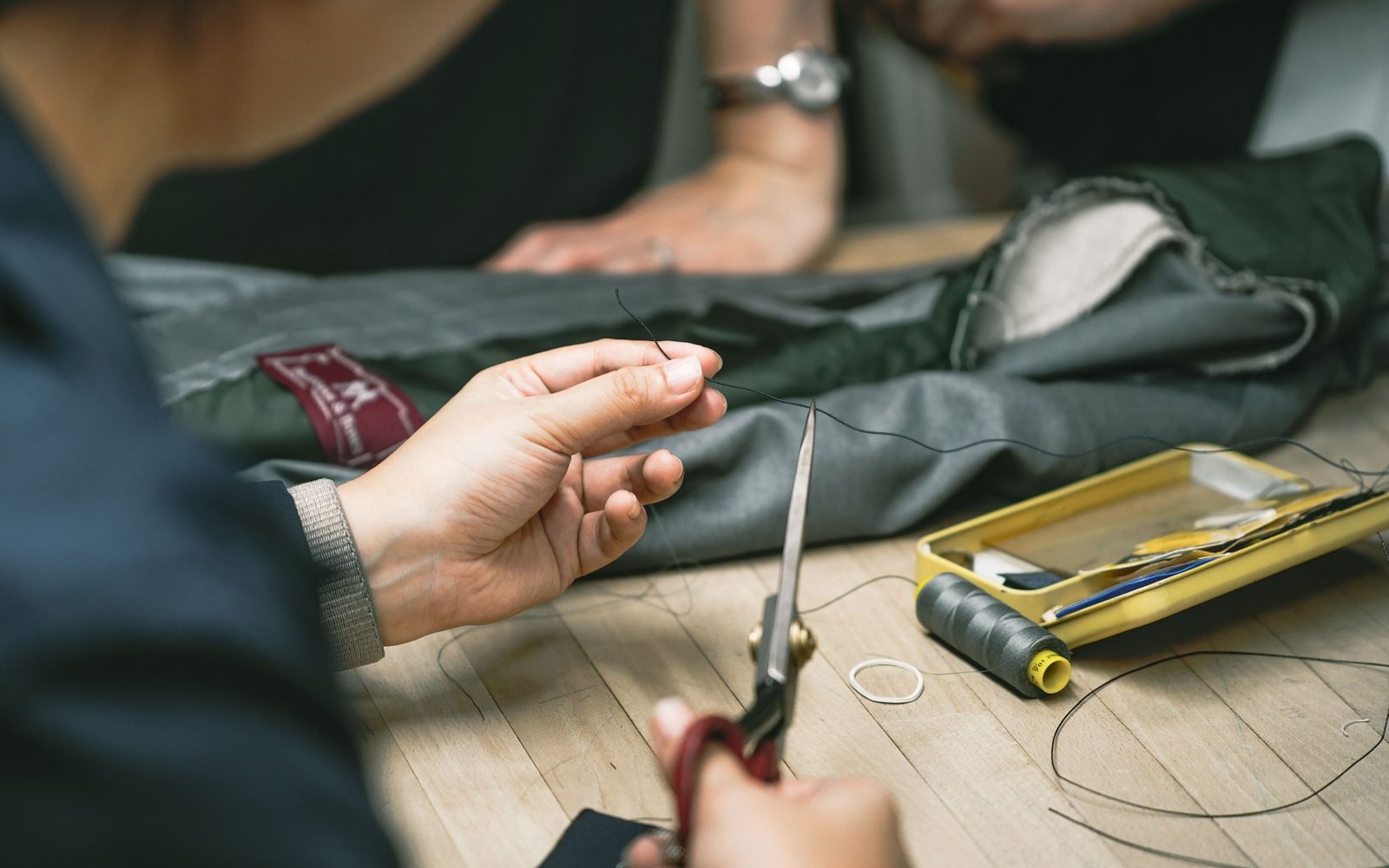 Thread, shears and a Buttons & Bows label on the cutting table in the shop